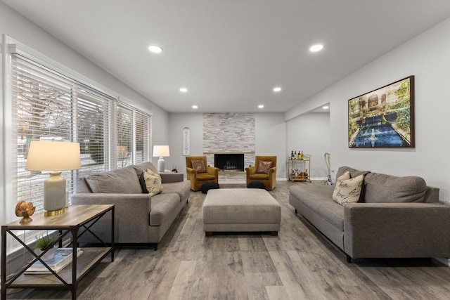 living room featuring recessed lighting, a fireplace, baseboards, and light wood-style floors