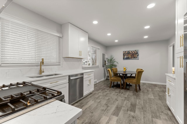 kitchen with white cabinetry, light wood-style flooring, recessed lighting, a sink, and stainless steel dishwasher