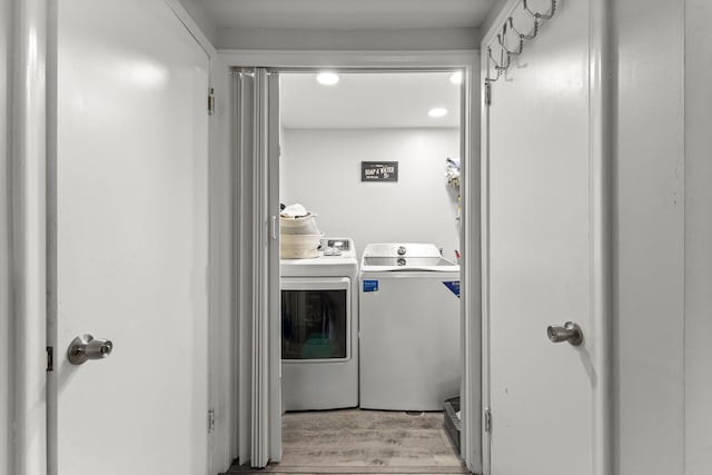 washroom with wood finished floors, laundry area, and washing machine and clothes dryer