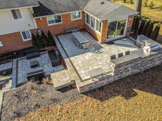 back of property featuring a patio, exterior kitchen, and a shingled roof