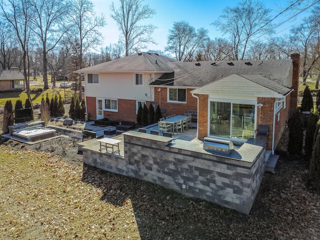 back of property featuring a patio area, an outdoor kitchen, a chimney, and brick siding