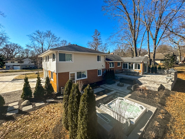 rear view of property with a patio, a jacuzzi, and brick siding