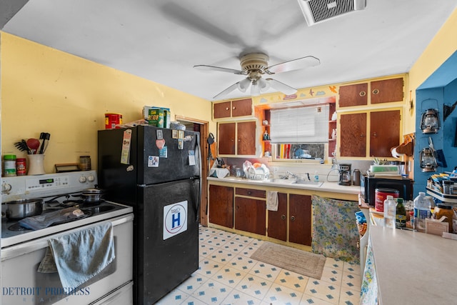 kitchen featuring visible vents, light floors, freestanding refrigerator, electric range, and a sink