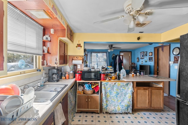 kitchen with a peninsula, a ceiling fan, black microwave, and light countertops