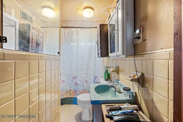 full bathroom featuring a shower with curtain, a wainscoted wall, tile walls, toilet, and tile patterned floors