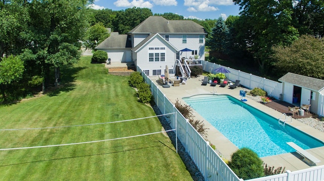 view of pool featuring an outbuilding, a yard, a fenced backyard, a diving board, and a patio area