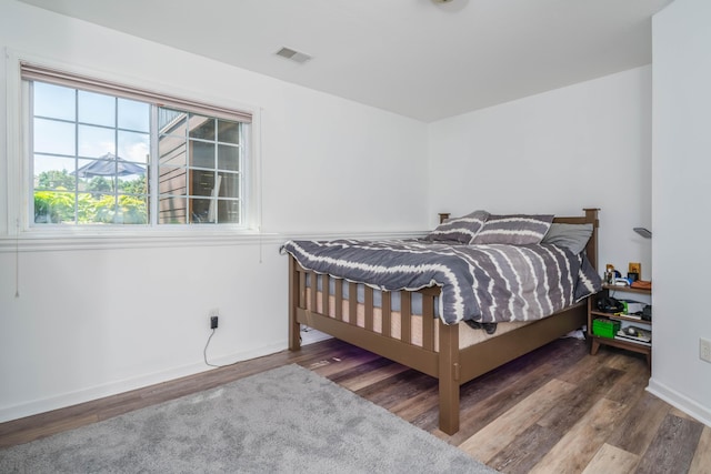 bedroom featuring wood finished floors, visible vents, and baseboards