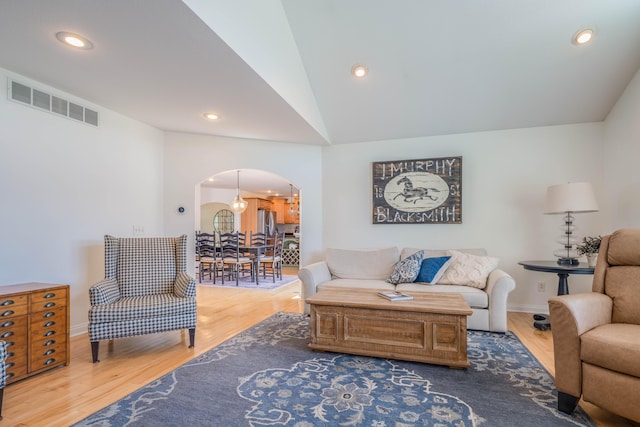 living area with wood finished floors, visible vents, recessed lighting, arched walkways, and vaulted ceiling