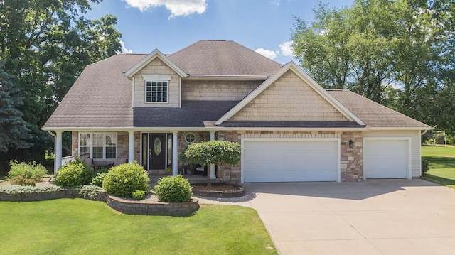 craftsman-style home with a porch, a front yard, driveway, stone siding, and an attached garage