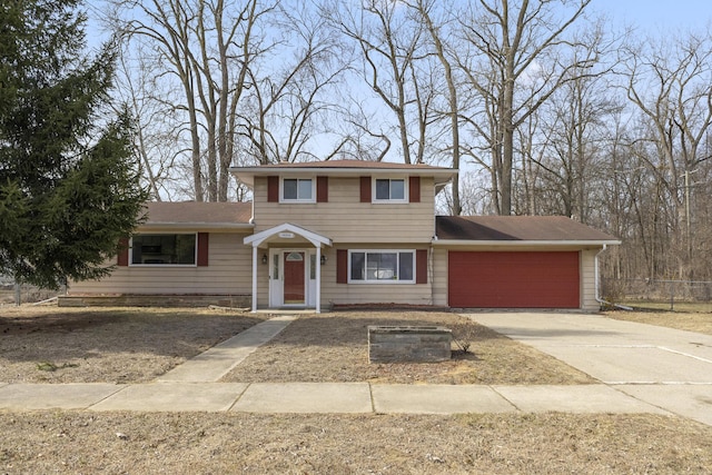 view of front of house with concrete driveway, an attached garage, and fence