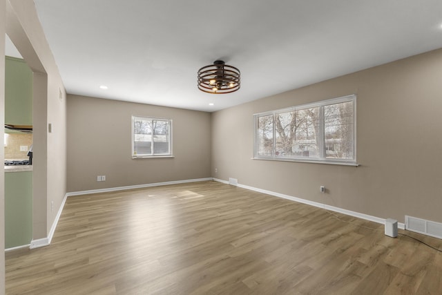 unfurnished room featuring light wood finished floors, visible vents, recessed lighting, and baseboards