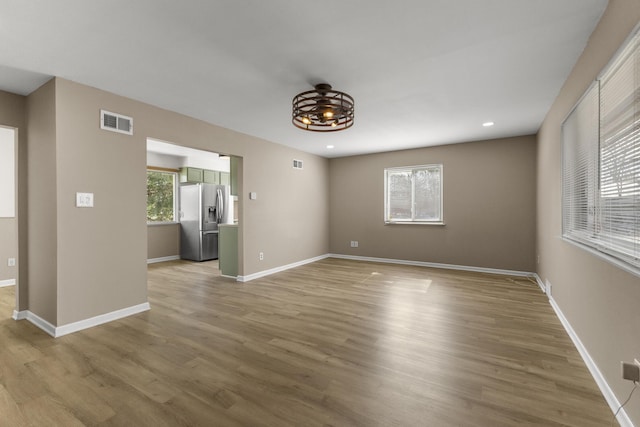 empty room featuring light wood-type flooring, visible vents, baseboards, and recessed lighting