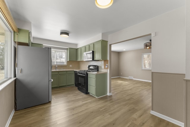 kitchen featuring a sink, appliances with stainless steel finishes, light countertops, and green cabinetry