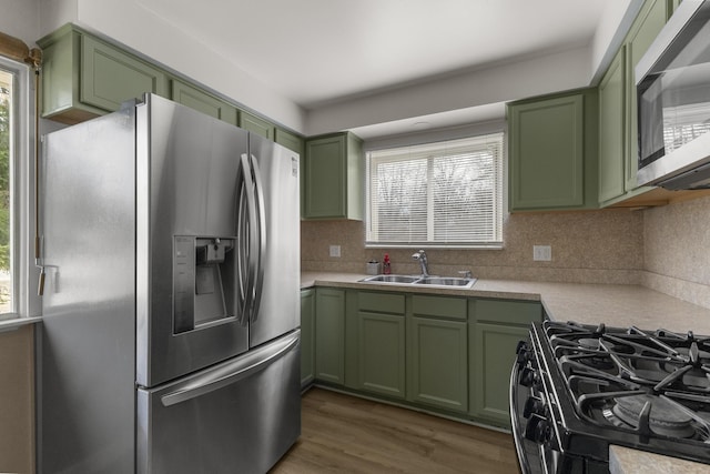 kitchen with a sink, dark wood-style floors, stainless steel appliances, light countertops, and green cabinetry