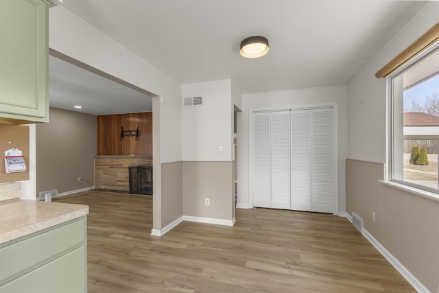 interior space featuring visible vents, light countertops, light wood-type flooring, a fireplace, and green cabinetry