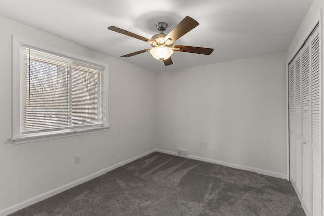 unfurnished bedroom with a closet, visible vents, dark carpet, and baseboards