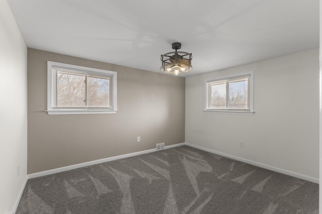 carpeted spare room featuring visible vents and baseboards