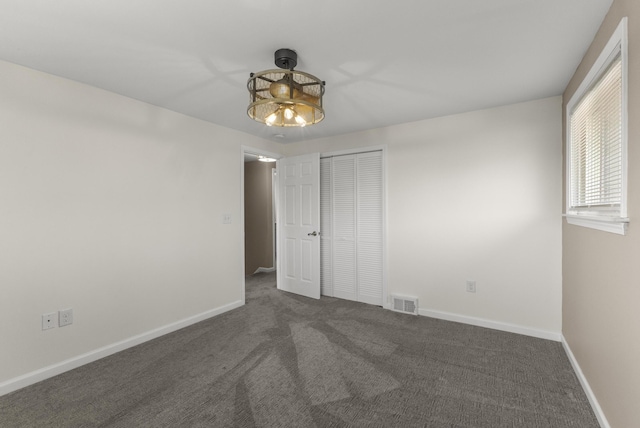 spare room with visible vents, baseboards, and dark carpet