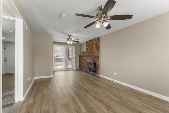 unfurnished living room with visible vents, baseboards, a brick fireplace, and light wood-style flooring