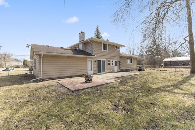 rear view of house with fence, a yard, a chimney, a fire pit, and a patio area