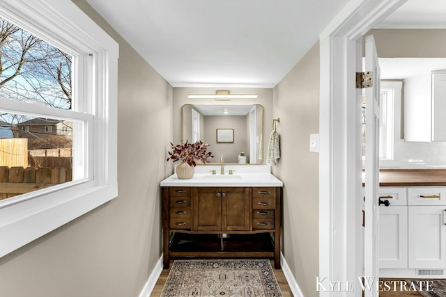 bathroom featuring visible vents, backsplash, vanity, and baseboards