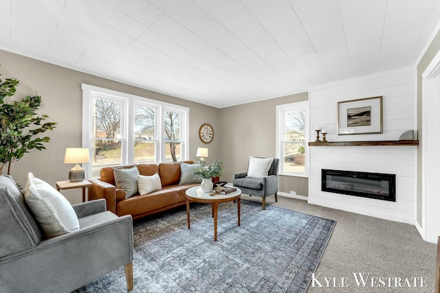 carpeted living room featuring baseboards and a glass covered fireplace