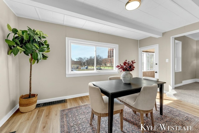 dining room with visible vents, beam ceiling, baseboards, and wood finished floors