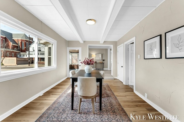 dining area with beam ceiling, baseboards, and wood finished floors