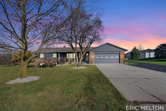 view of front of house featuring a front lawn, driveway, board and batten siding, a garage, and brick siding