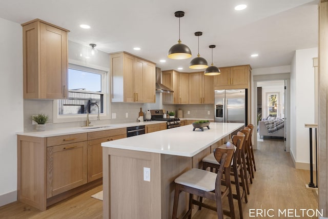 kitchen with a kitchen bar, a sink, a kitchen island, appliances with stainless steel finishes, and light wood finished floors