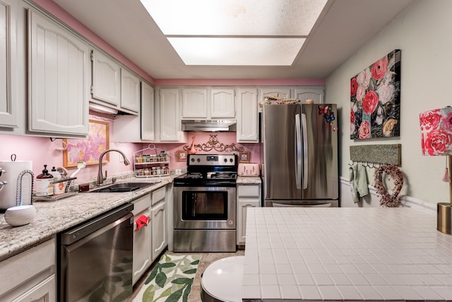 kitchen featuring under cabinet range hood, appliances with stainless steel finishes, light countertops, and a sink