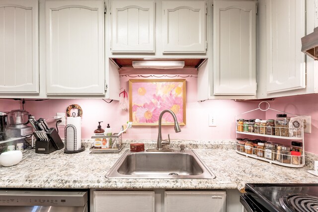 kitchen featuring dishwasher, white cabinetry, light countertops, and a sink