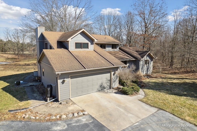 view of front of home featuring a shingled roof, a front lawn, concrete driveway, a chimney, and a garage