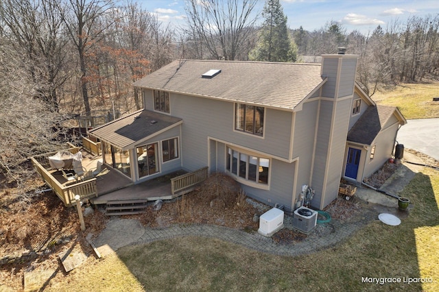 back of house featuring central air condition unit, a lawn, roof with shingles, a wooden deck, and a chimney