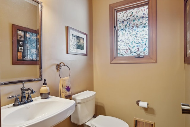 bathroom featuring visible vents, a healthy amount of sunlight, toilet, and a sink