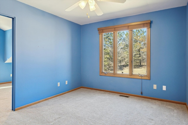 carpeted spare room featuring plenty of natural light, a ceiling fan, visible vents, and baseboards