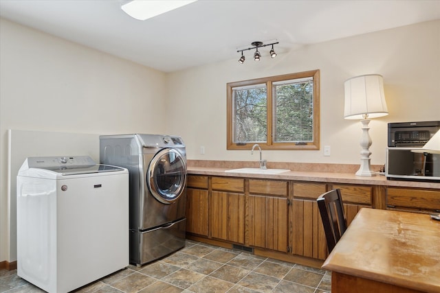 clothes washing area with cabinet space, independent washer and dryer, and a sink