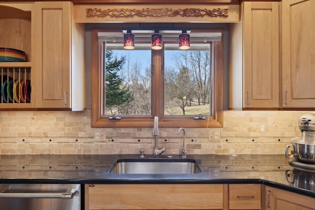 kitchen with light brown cabinets, a sink, decorative backsplash, stainless steel dishwasher, and dark countertops