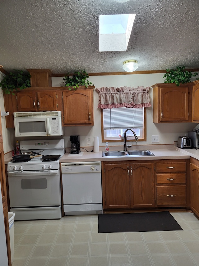 kitchen featuring a sink, white appliances, light floors, and a skylight