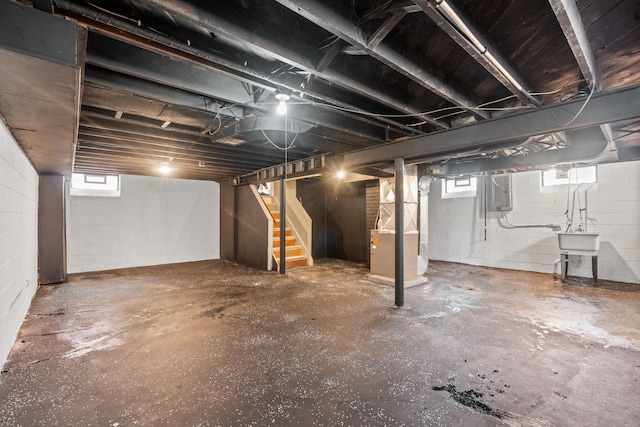 below grade area with heating unit, stairway, electric panel, and a sink