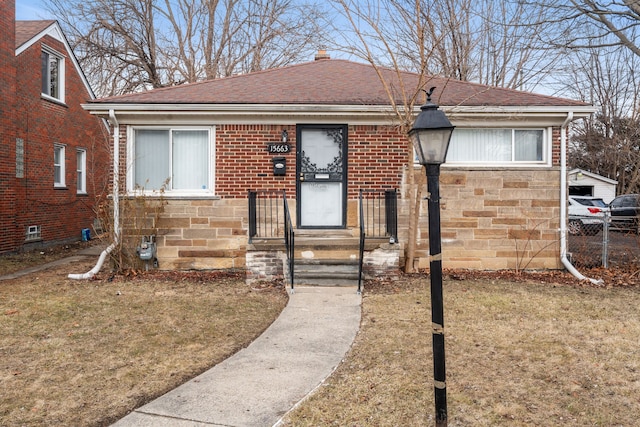 bungalow-style house featuring a front yard, stone siding, and roof with shingles