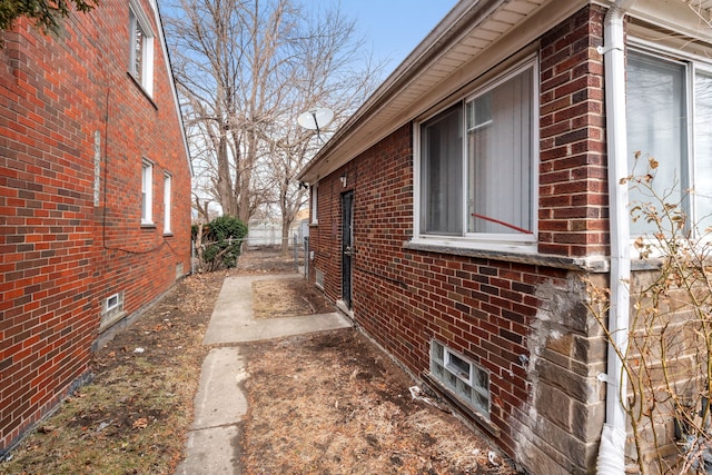 view of side of home featuring brick siding and fence