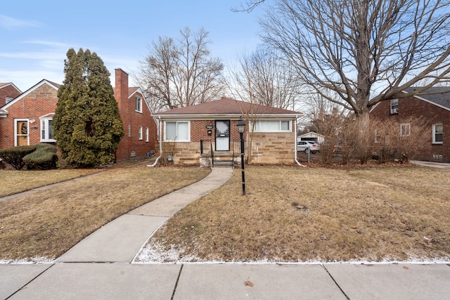 bungalow-style house with brick siding, a chimney, and a front lawn