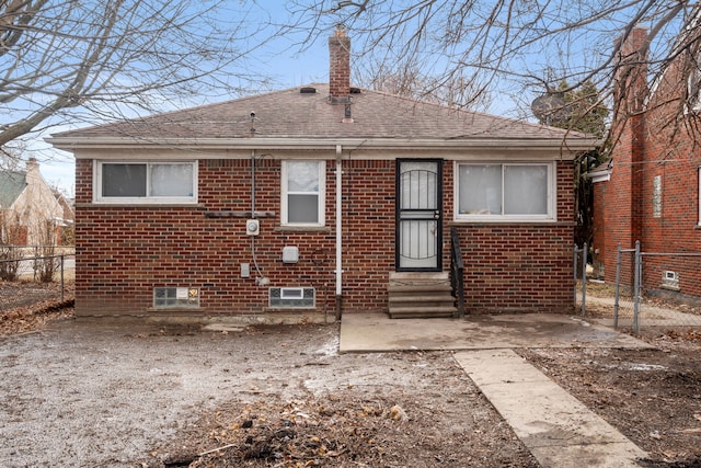 back of house with fence, a shingled roof, brick siding, and entry steps