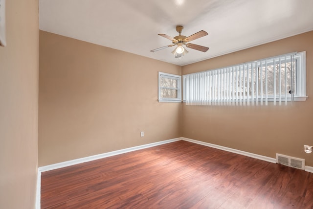 spare room featuring baseboards, wood finished floors, visible vents, and ceiling fan