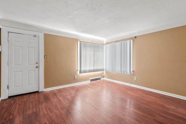 unfurnished room featuring a textured ceiling, wood finished floors, visible vents, and baseboards