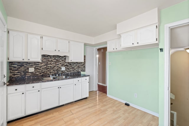 kitchen with a sink, decorative backsplash, light wood-style floors, and white cabinetry