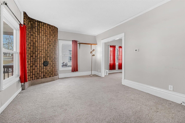 empty room with visible vents, baseboards, carpet flooring, and crown molding