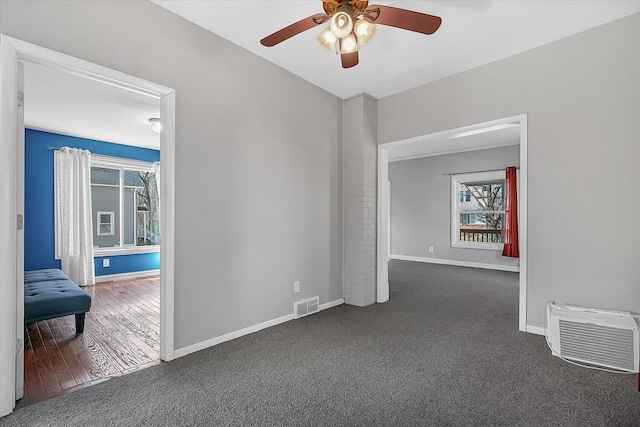 empty room featuring a ceiling fan, a healthy amount of sunlight, visible vents, and baseboards