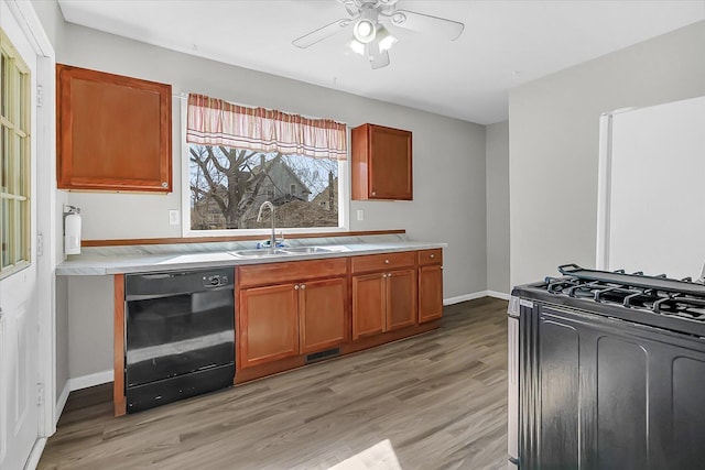 kitchen with visible vents, black appliances, light wood-style flooring, a sink, and light countertops